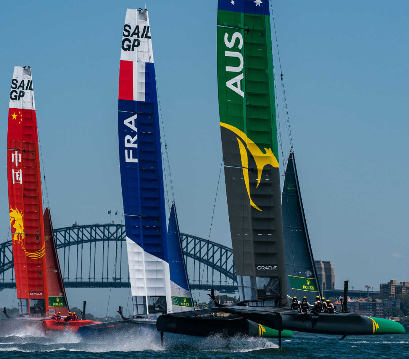 SailGP foiling catamarans racing at speed with city skyline backdrop