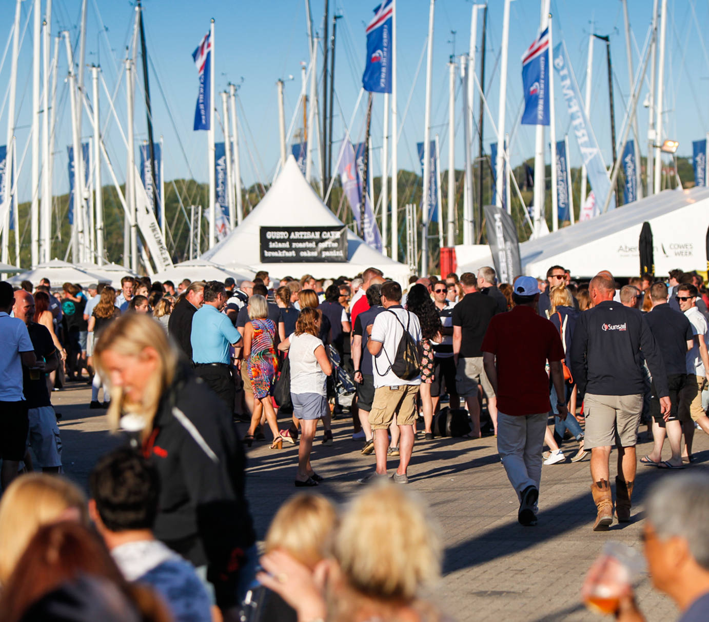 Crowds enjoying Cowes Week on the Isle of Wight with marina and sponsor flags