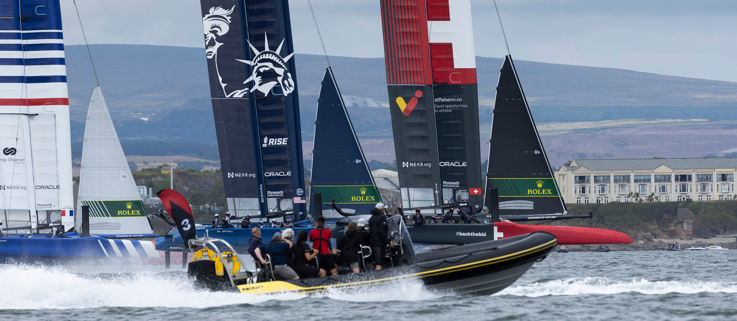 VIP guests onboard a RIB watching high-performance racing yachts on the Solent during a major sailing event with branded foiling teams competing