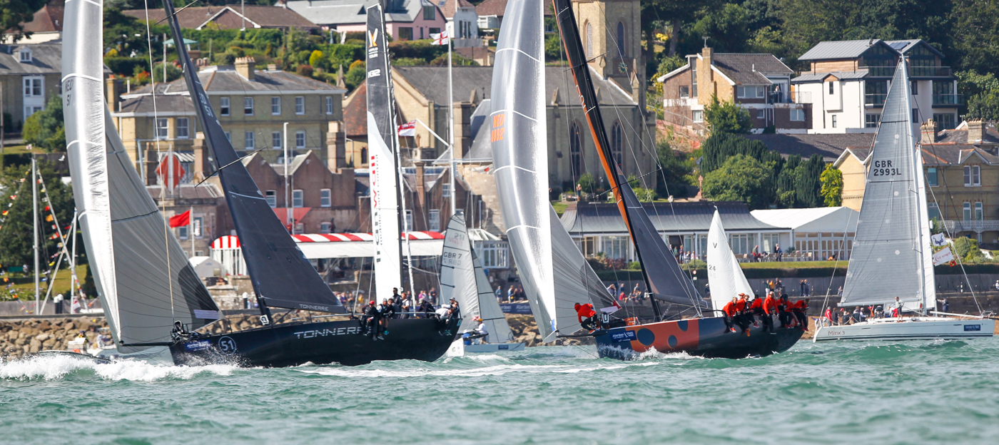 Competitive yacht racing off Cowes during a Solent sailing regatta with spectators and corporate hospitality ashore