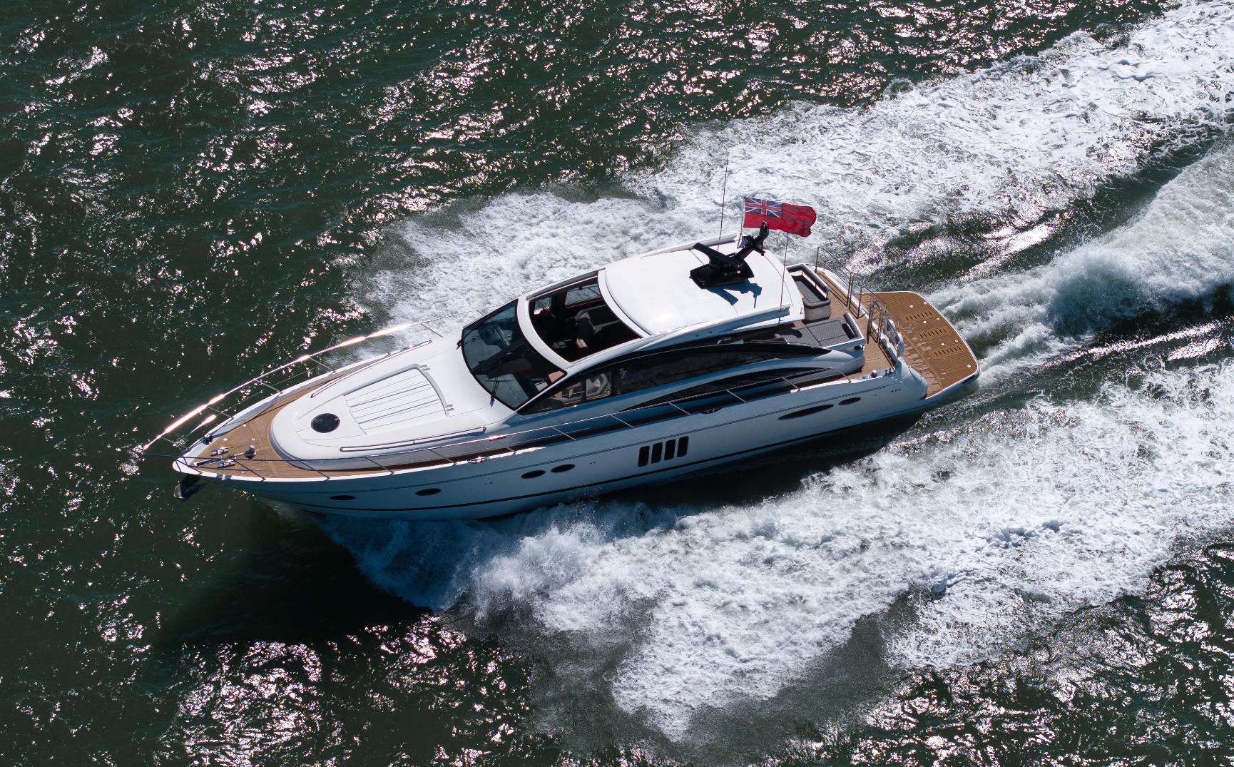 Aerial view of Princess V65 Varka luxury motor yacht cruising through open water with wake behind for private yacht charter with Solent Events
