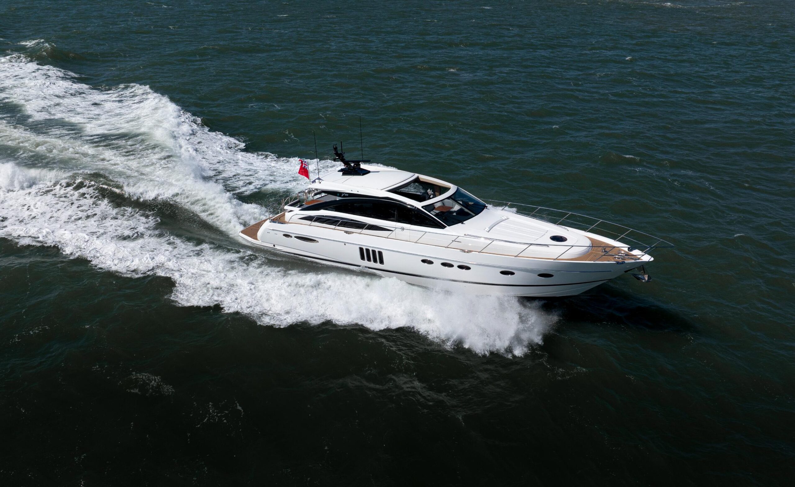 Aerial view of Princess V65 Varka luxury motor yacht cruising at speed across open water for private yacht charter with Solent Events