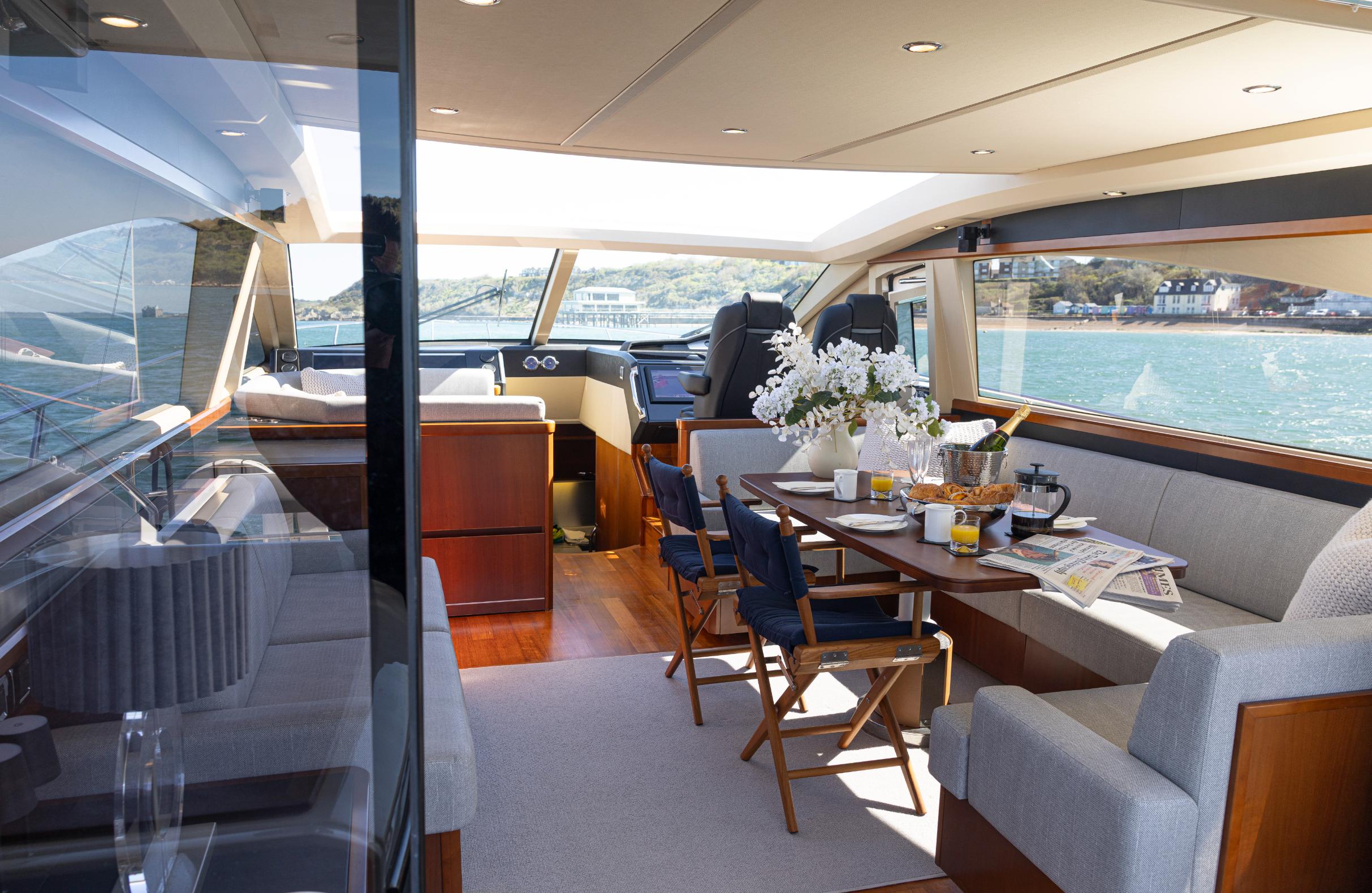 Princess V65 Varka interior saloon with luxury dining table, lounge seating and panoramic sea views for private yacht charter with Solent Events